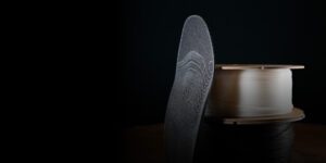 An orthotic printed with Mosaic Aero stacked up beside two filament spools