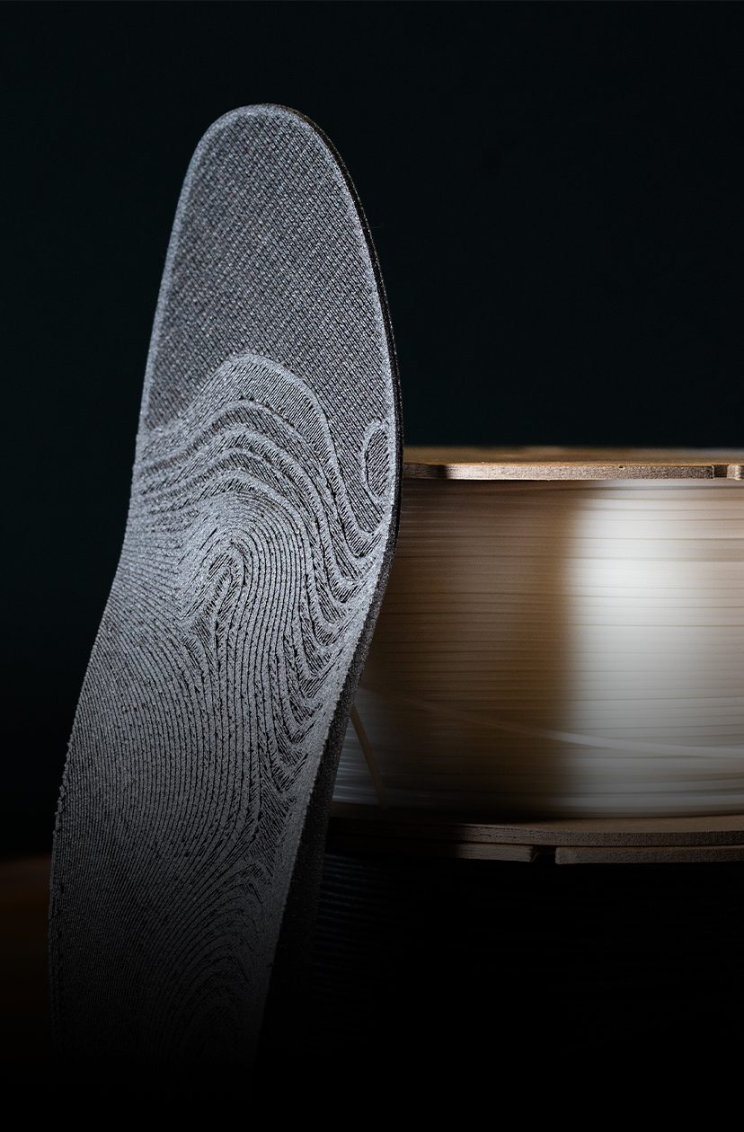 An orthotic printed with Mosaic Aero stacked up beside two filament spools